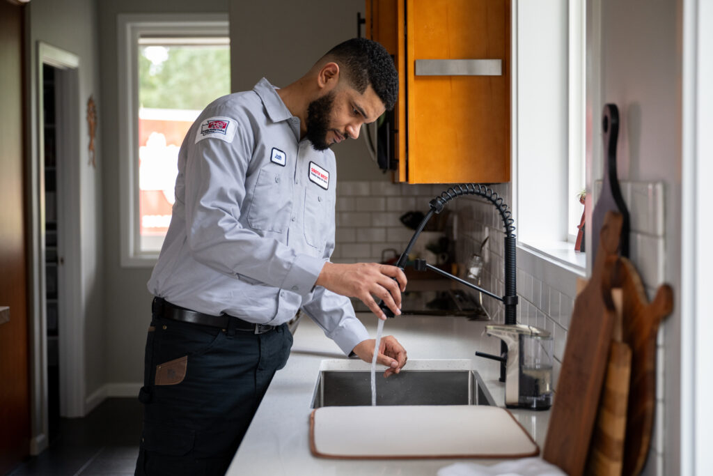 Plumber working on faucet in Seattle, WA.