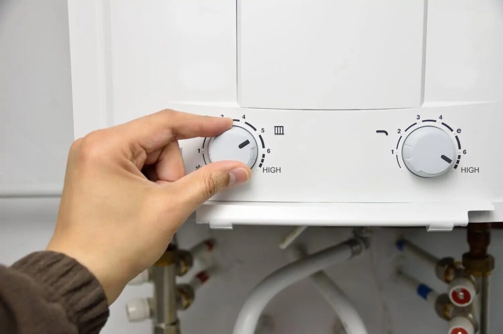 Tankless water heater knob being adjusted by a hand.